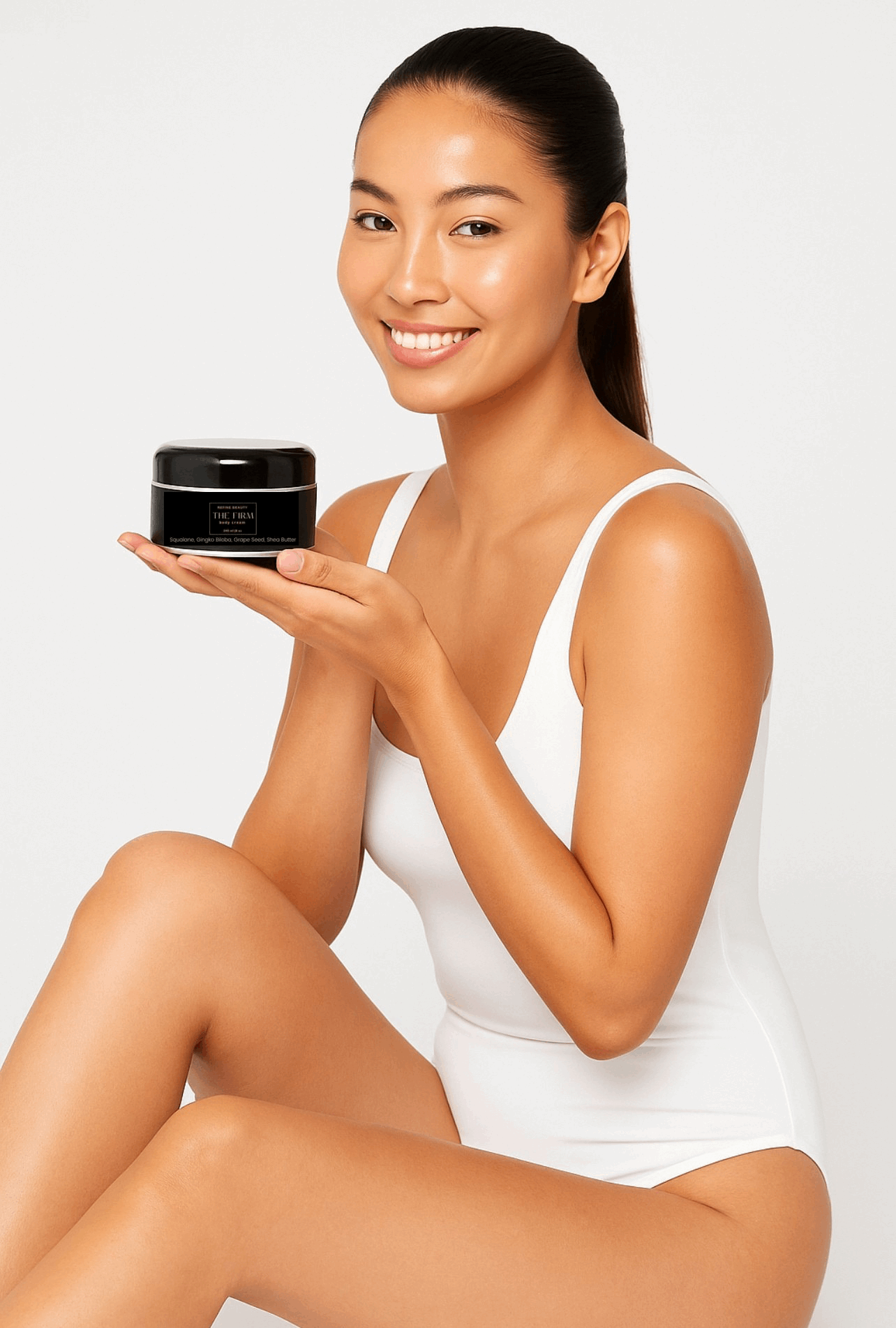 Model wearing white and holding Refine Beauty The Firm Body Cream
