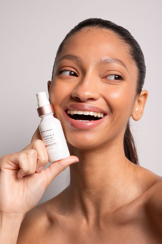 Refine Beauty Model holding a Vitamin C Serum with Hyaluronic Acid + Niacinamide on white background 