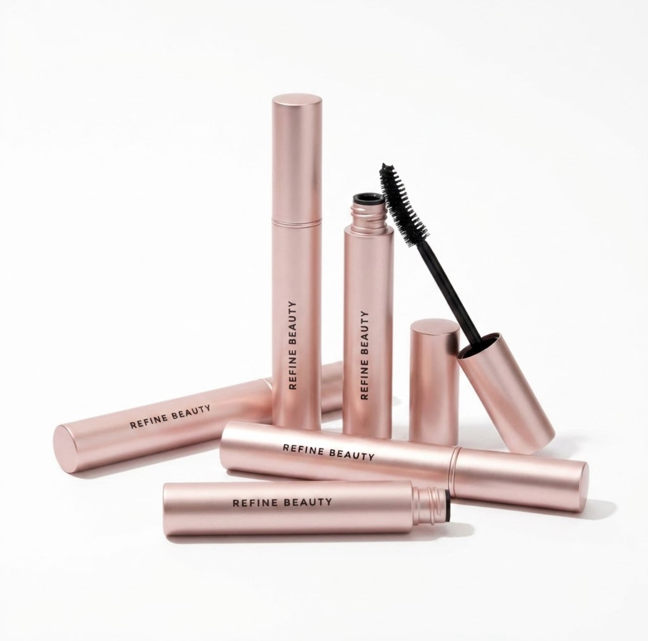 Rose gold Refine Beauty Volume mascara  tubes on a white background