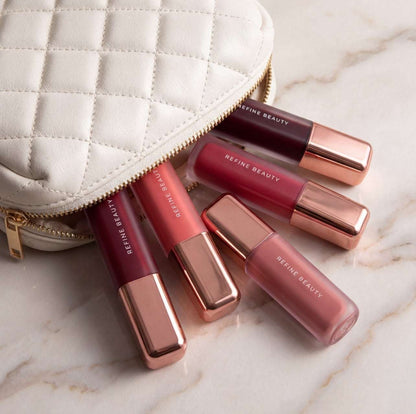 Refine Beauty liquid blush on a marble surface with a white quilted pouch.