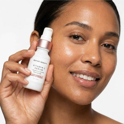 Woman holding a bottle of Refine Beauty Vitamin C Serum against a white background