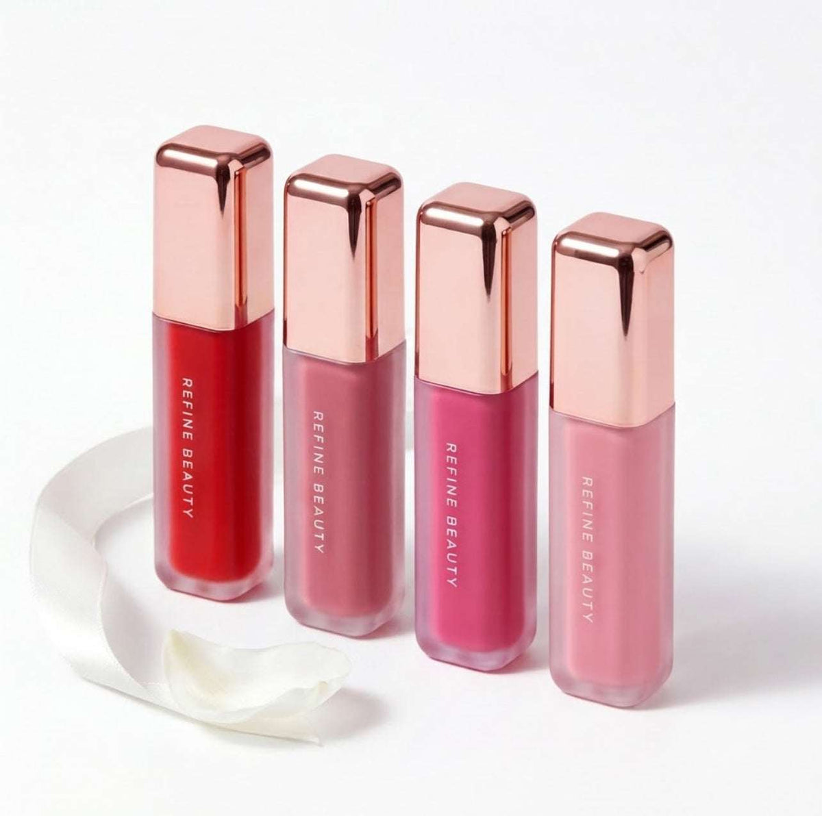 Four Refine Beauty blushes with rose gold caps on a white background