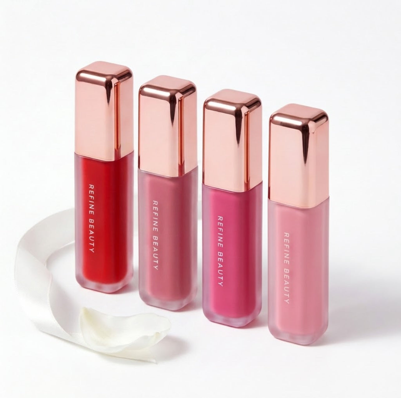 Four Refine Beauty blushes with rose gold caps on a white background