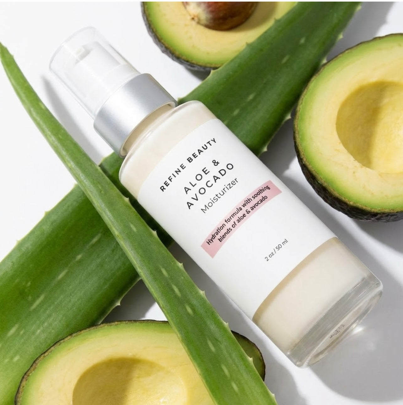 Aloe vera and avocado slices with a bottle of Refine Beauty Aloe & Avocado Moisturizer on a white background