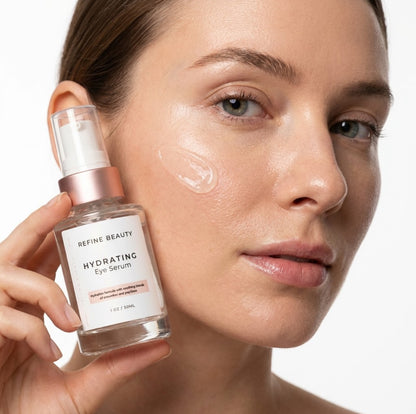 Woman holding a bottle of Refine Beauty Hydrating Eye Serum with product on her face.