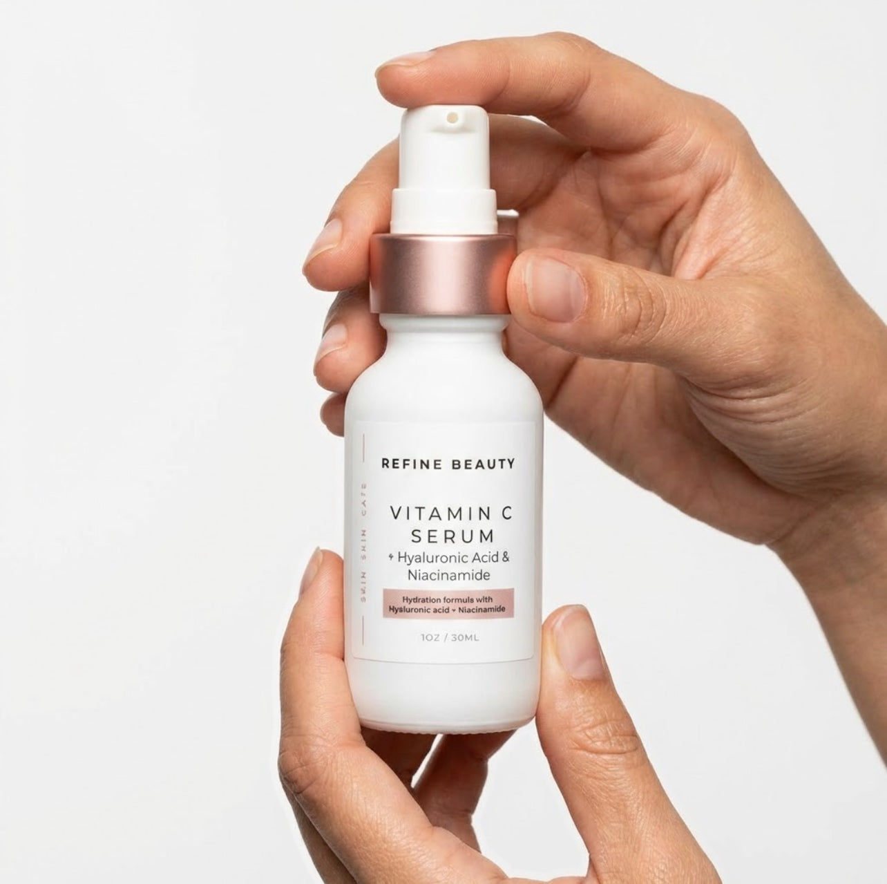 Hand holding a bottle of Refine Beauty Vitamin C Serum against a light background