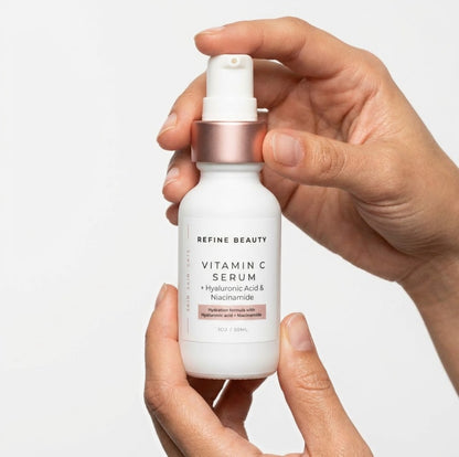 Hand holding a bottle of Refine Beauty Vitamin C Serum against a light background