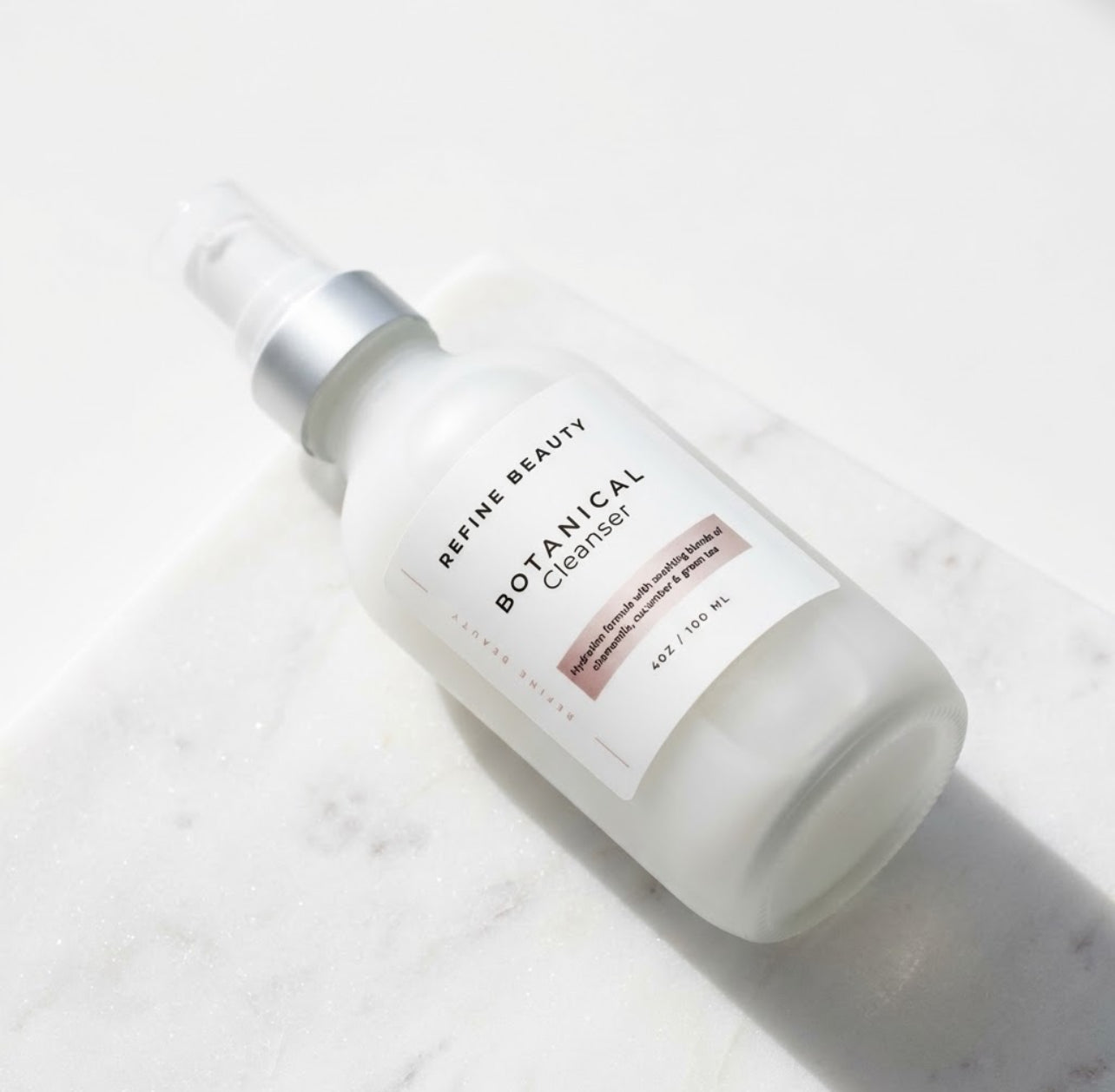Bottle of Refine Beauty Botanical Cleanser on a light marble background
