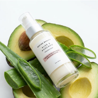 Refine Beauty Aloe & Avocado Moisturizer on sliced avocados with aloe leaves.