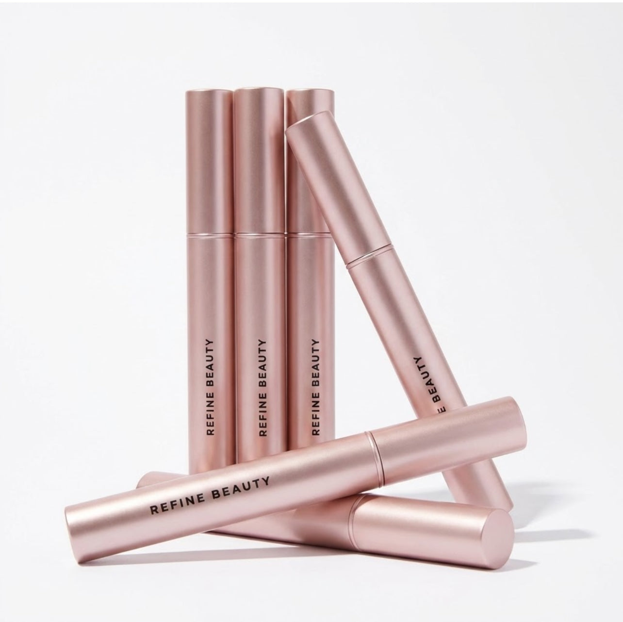 Rose gold mascara beauty products with Refine Beauty branding on a white background