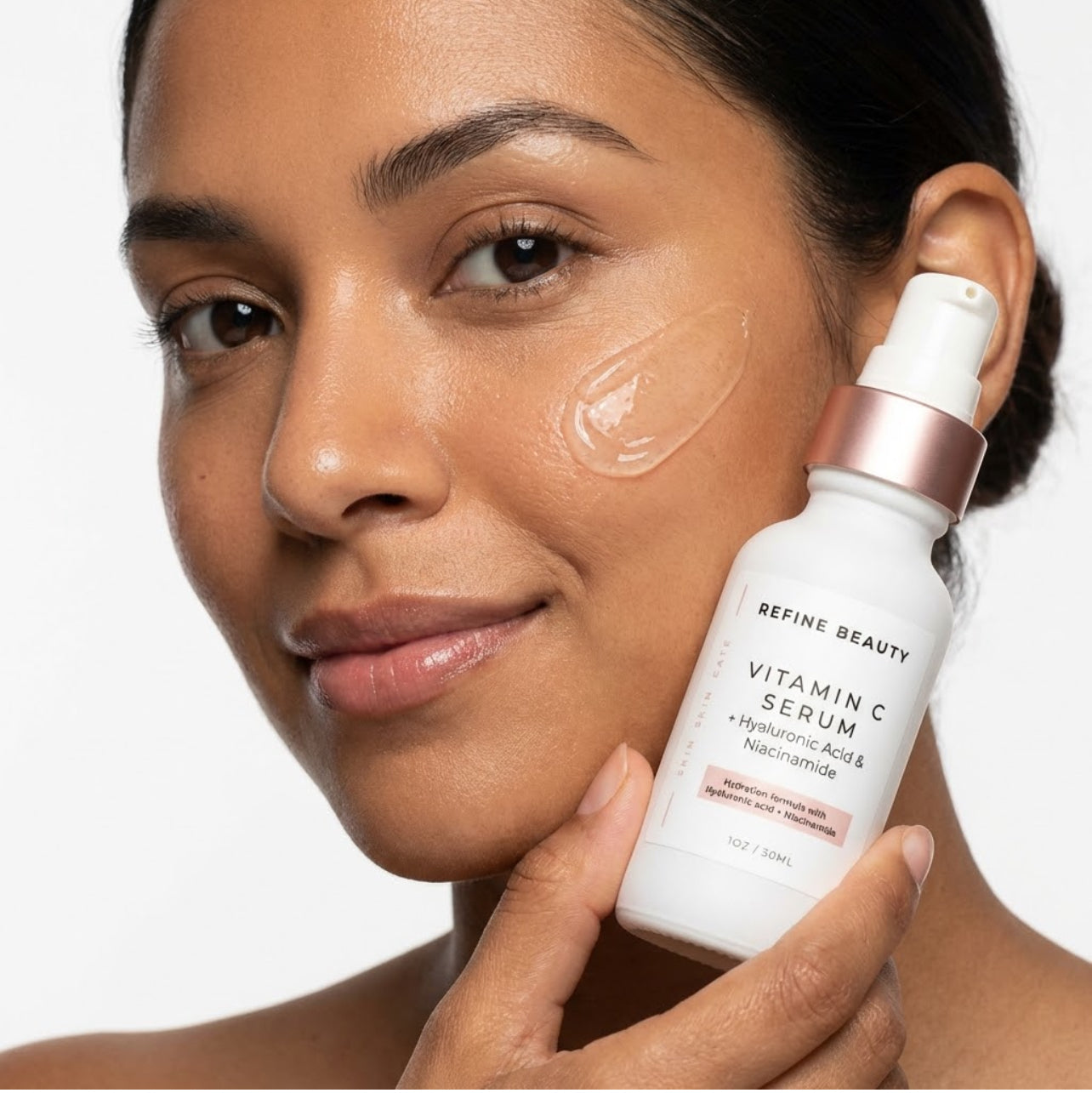 Woman applying Refine Beauty Vitamin C Serum skincare serum to her face with a white background