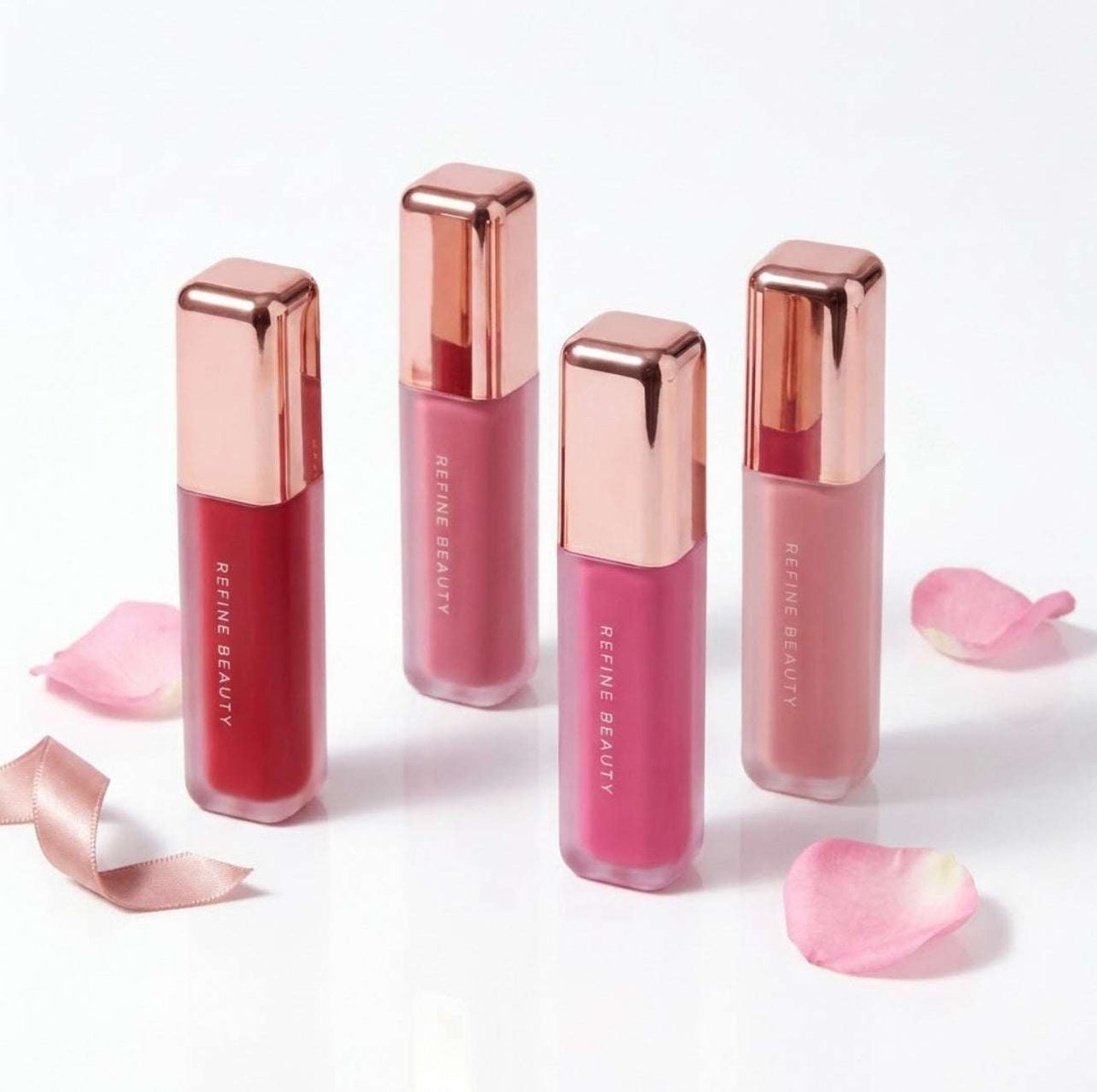 Refine Beauty blush with rose gold caps on a white background with pink petals.