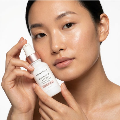 Woman holding a Refine Beauty skincare serum bottle with a neutral background