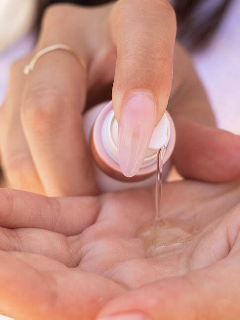 Model holding and pumping out Vitamin C Serum with Hyaluronic Acid + Niacinamide for fine lines and wrinkles, acne, hyperpigmentation for an improved appearance and texture